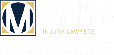Owens & Minor Injury Lawyers logo with a large white M on a navy circle and gold corner accents, plus the text 'OWENS & ... INJURY LAWYERS' in gold.